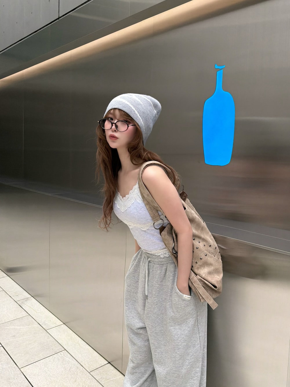 ホワイト系のキャミソール、ブラック系のデニムジャケット、グレー系のスウェットパンツを着用したレディースの春コーディネートの2枚目の写真