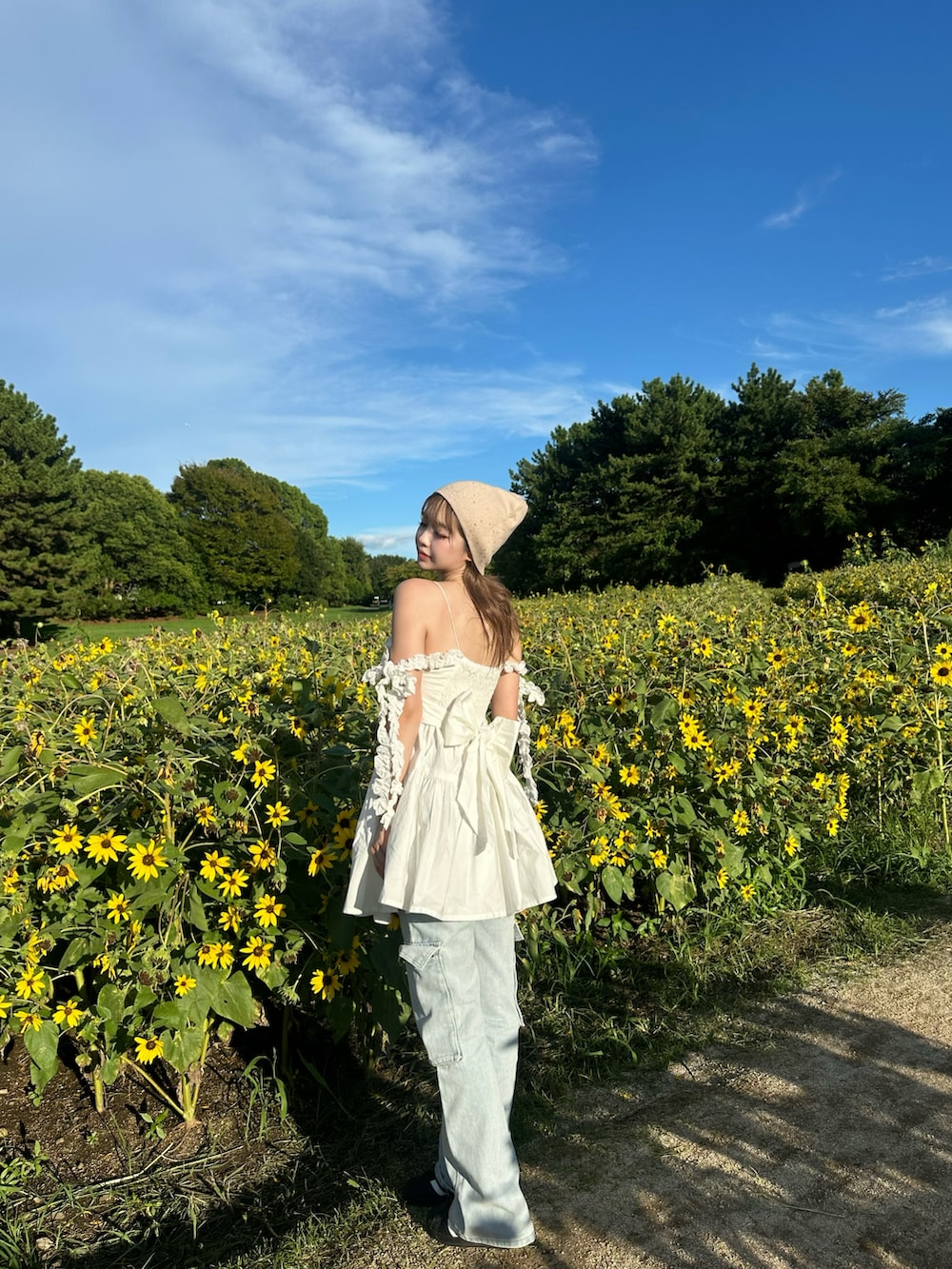 ホワイト系のチュニック、ブルー系のパンツ、ホワイト系のショルダーバッグを着用したレディースの夏コーディネートの3枚目の写真