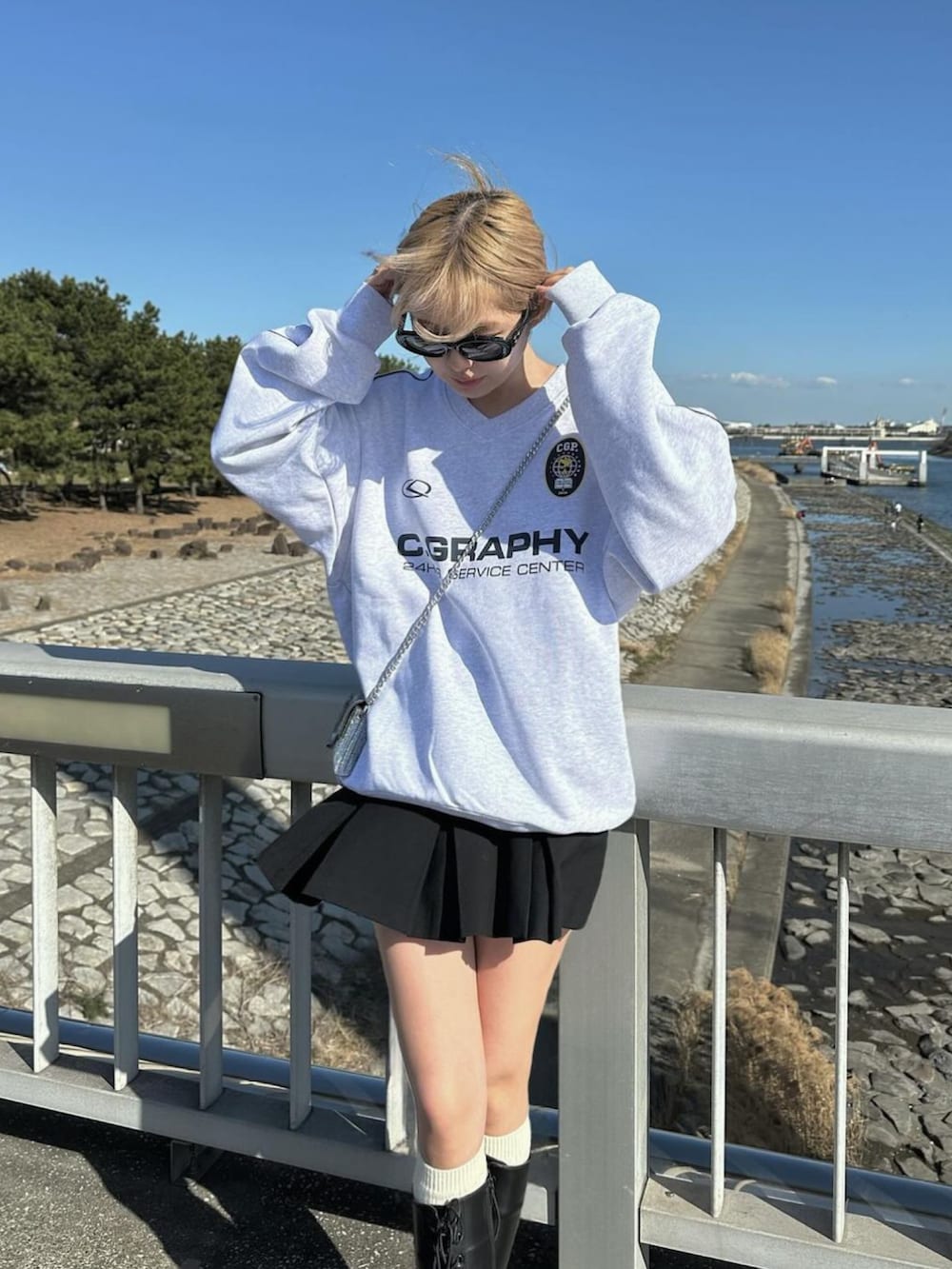 グレー系のスウェット、ブラック系のブーツ、ブラック系のスカートを着用したレディースの春コーディネートの2枚目の写真