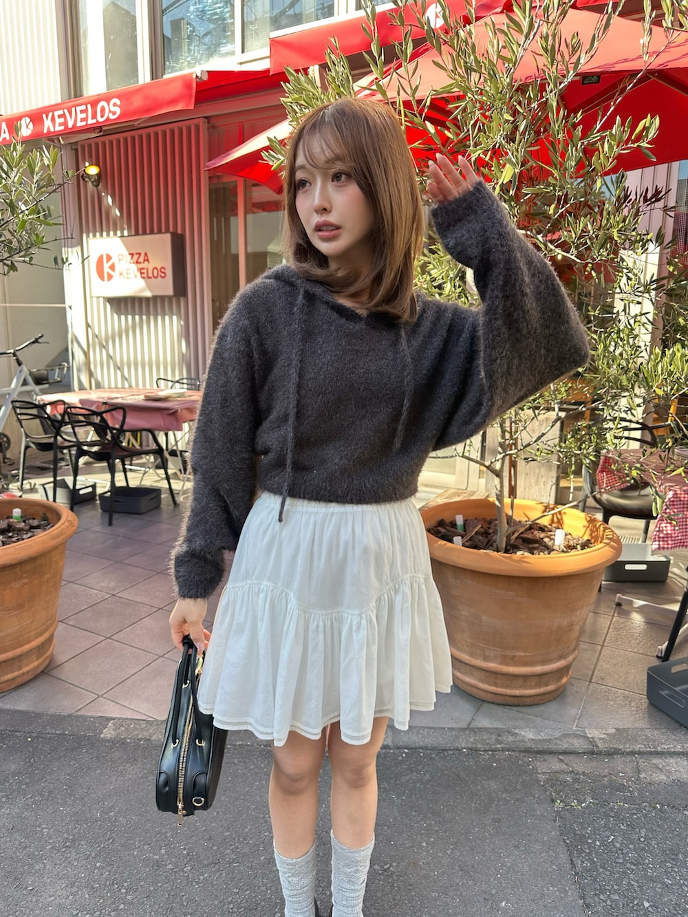 ブラック系のニット/セーター、ホワイト系のスカート、ブラック系のボストンバッグを着用したレディースの冬コーディネートの2枚目の写真