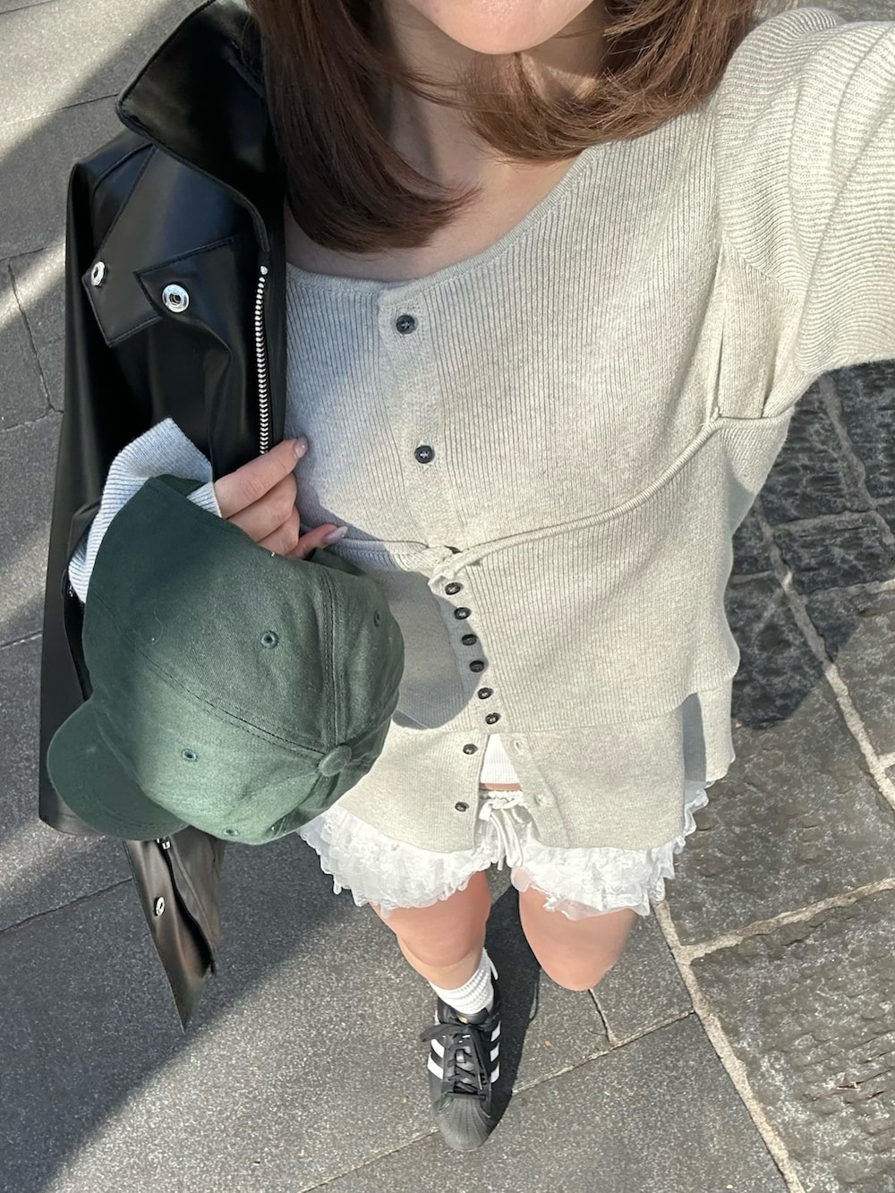 ブラック系のテーラードジャケット、ブラック系のスニーカー、ホワイト系のカーディガン/ボレロを着用したレディースの冬コーディネートの2枚目の写真