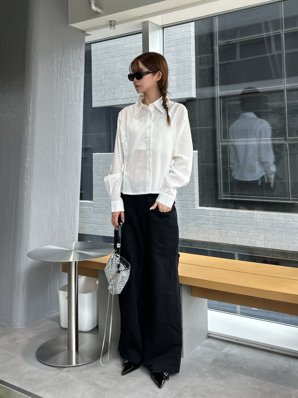 ブラック系のデニムパンツ、シルバー系のバッグ、ホワイト系のシャツ/ブラウスを着用したレディースの夏コーディネートの2枚目の写真