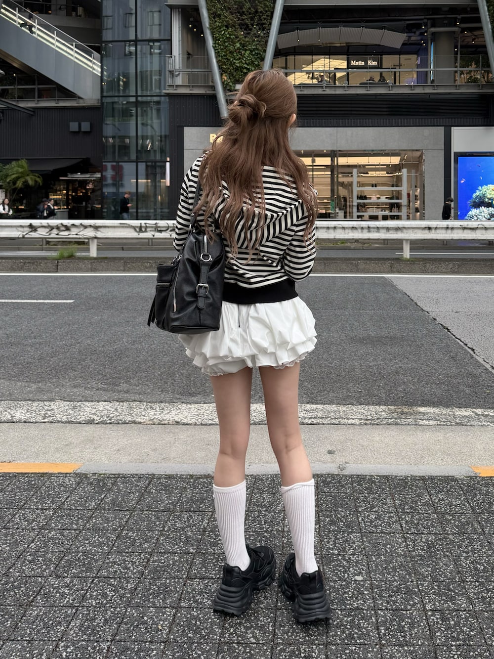 ホワイト系のパーカー、ホワイト系のスカート、ブラック系のスニーカーを着用したレディースの春コーディネートの4枚目の写真