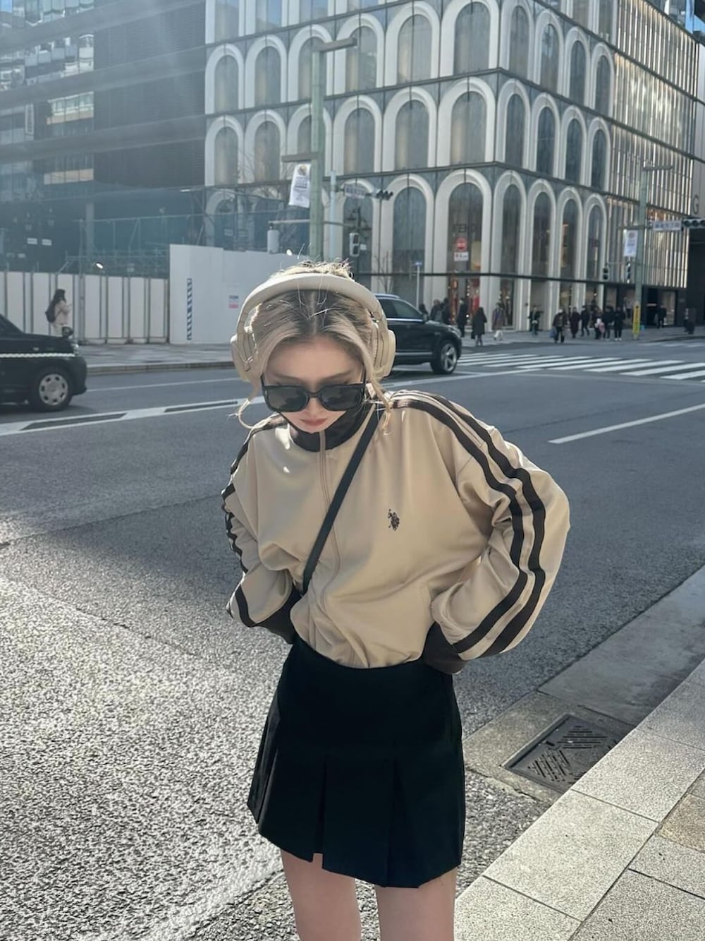 ベージュ系のジャージ、ブラック系のスカート、ブラック系のブーツを着用したレディースの春コーディネートの2枚目の写真