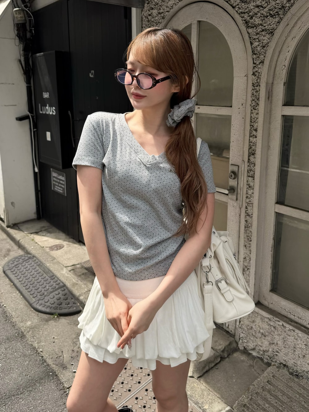 ホワイト系のスカート、グレー系のTシャツ/カットソー、ブラック系のショルダーバッグを着用したレディースの春コーディネートの3枚目の写真
