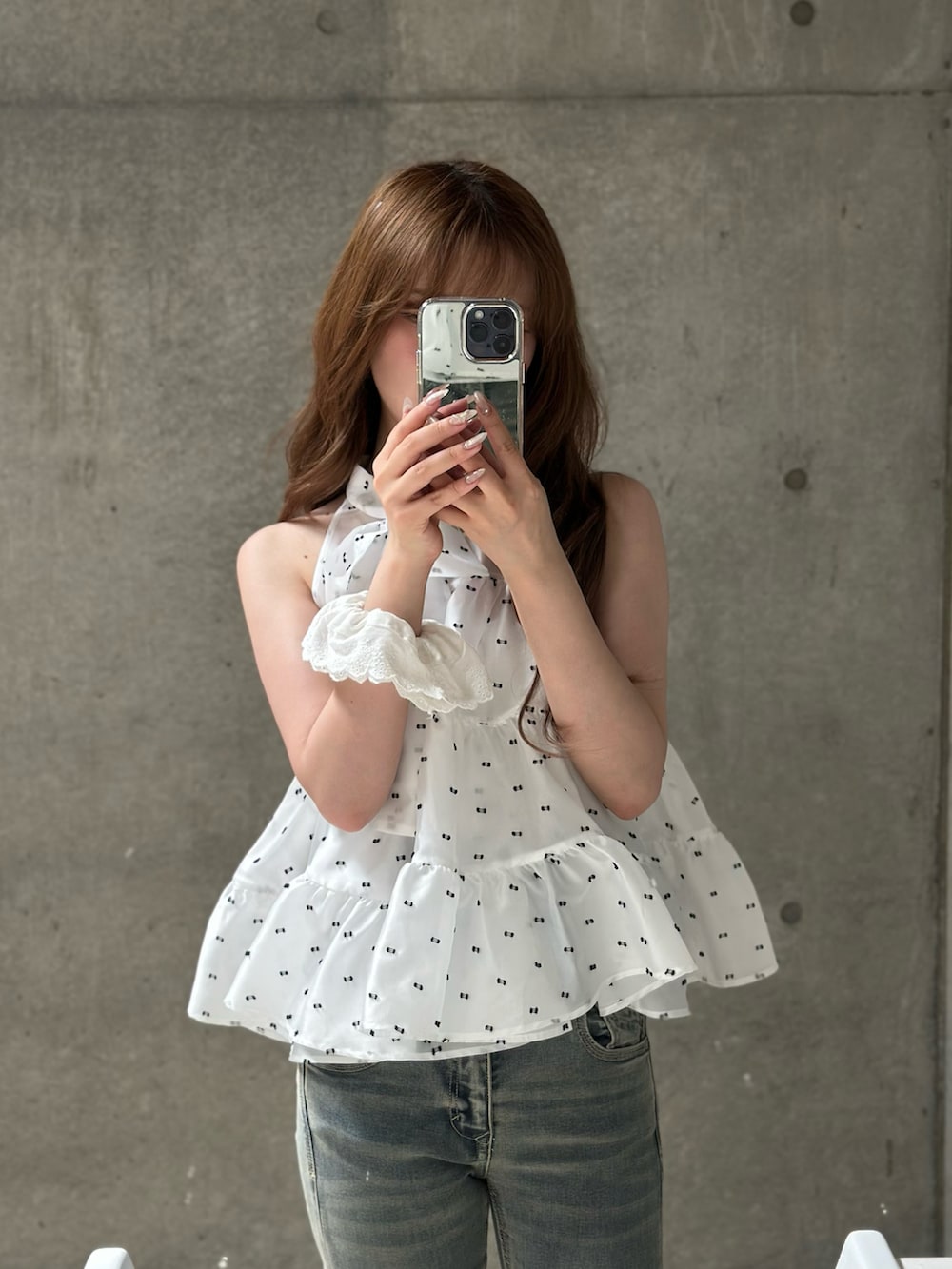ブルー系のデニムパンツ、ベージュ系のバッグ、ホワイト系のスニーカーを着用したレディースの春コーディネートの2枚目の写真