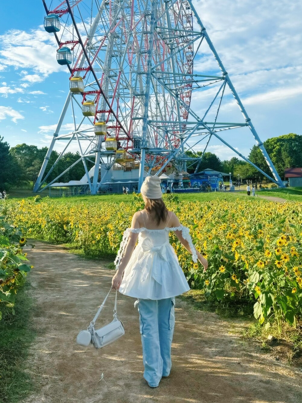 ホワイト系のチュニック、ブルー系のパンツ、ホワイト系のショルダーバッグを着用したレディースの夏コーディネートの2枚目の写真