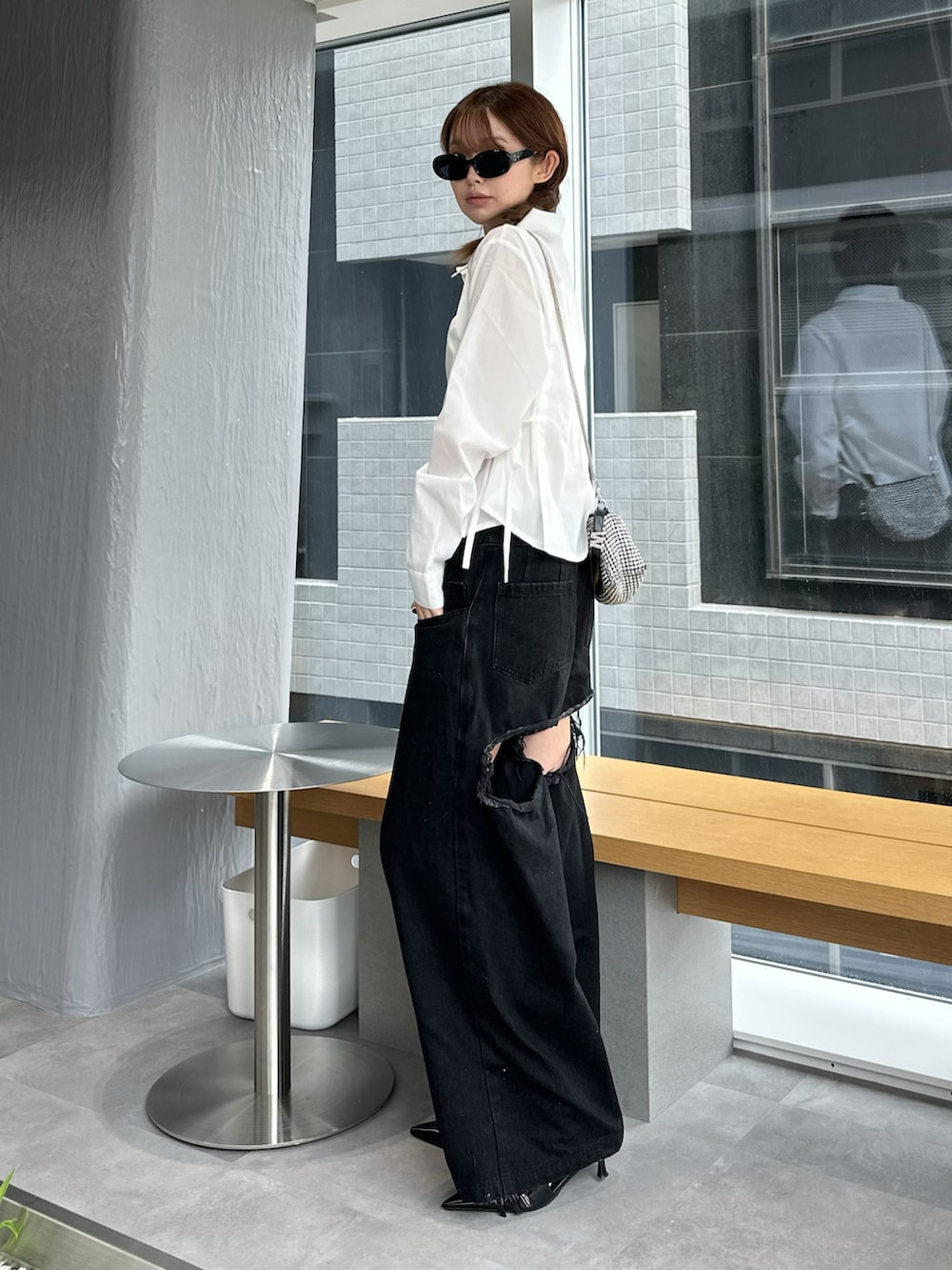 ブラック系のデニムパンツ、シルバー系のバッグ、ホワイト系のシャツ/ブラウスを着用したレディースの夏コーディネートの3枚目の写真