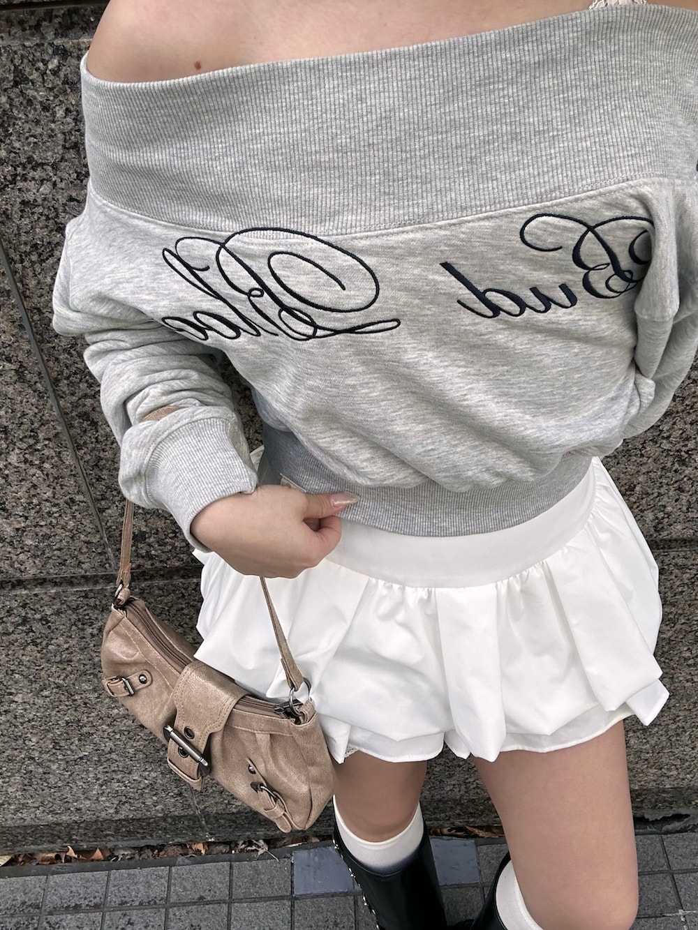 グレー系のスウェット、ホワイト系のスカート、ブラック系のブーツを着用したレディースの冬コーディネートの3枚目の写真