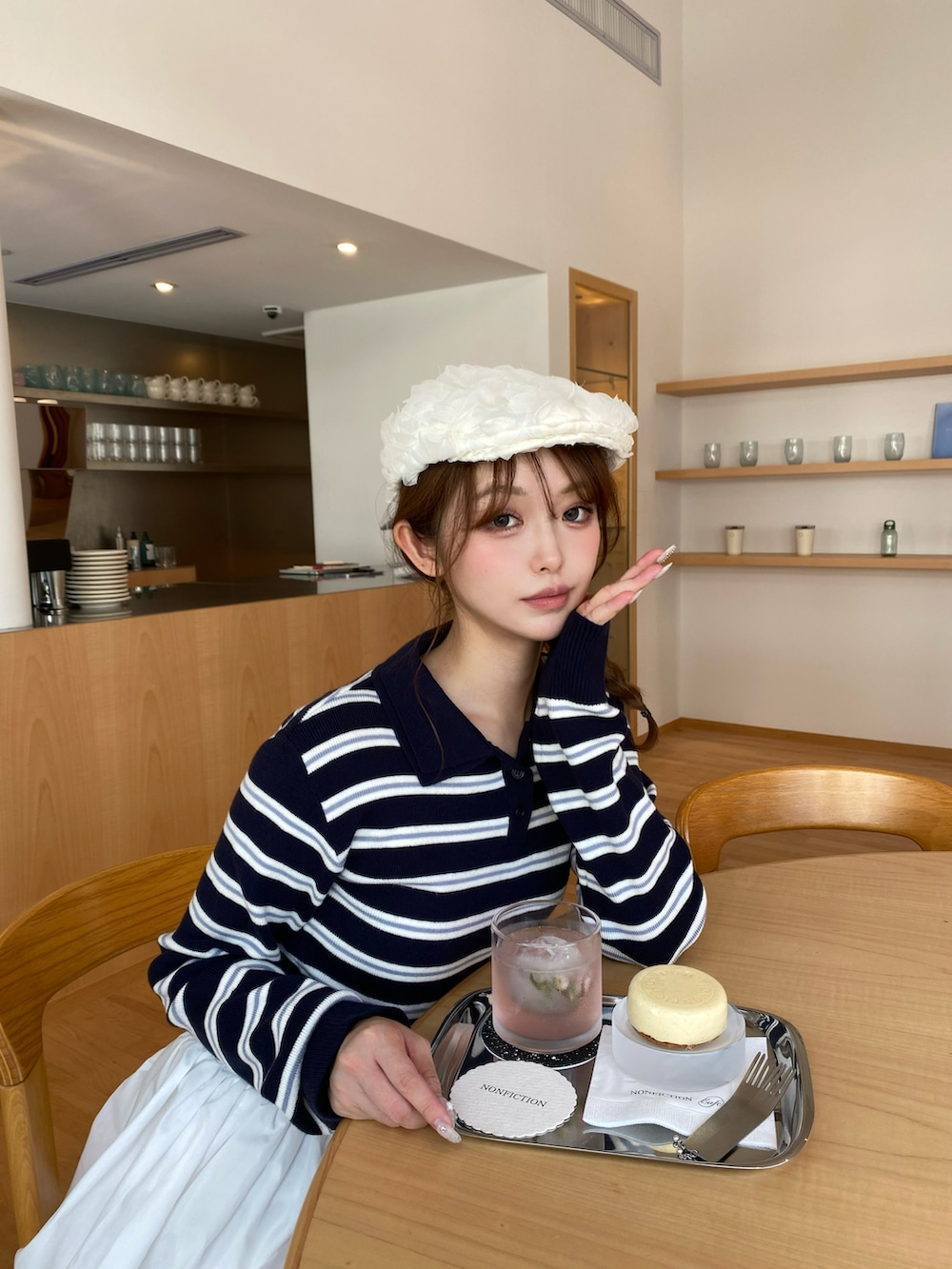 ホワイト系のスカート、ブルー系のトップス、ブラウン系のブーツを着用したレディースの秋コーディネートの2枚目の写真
