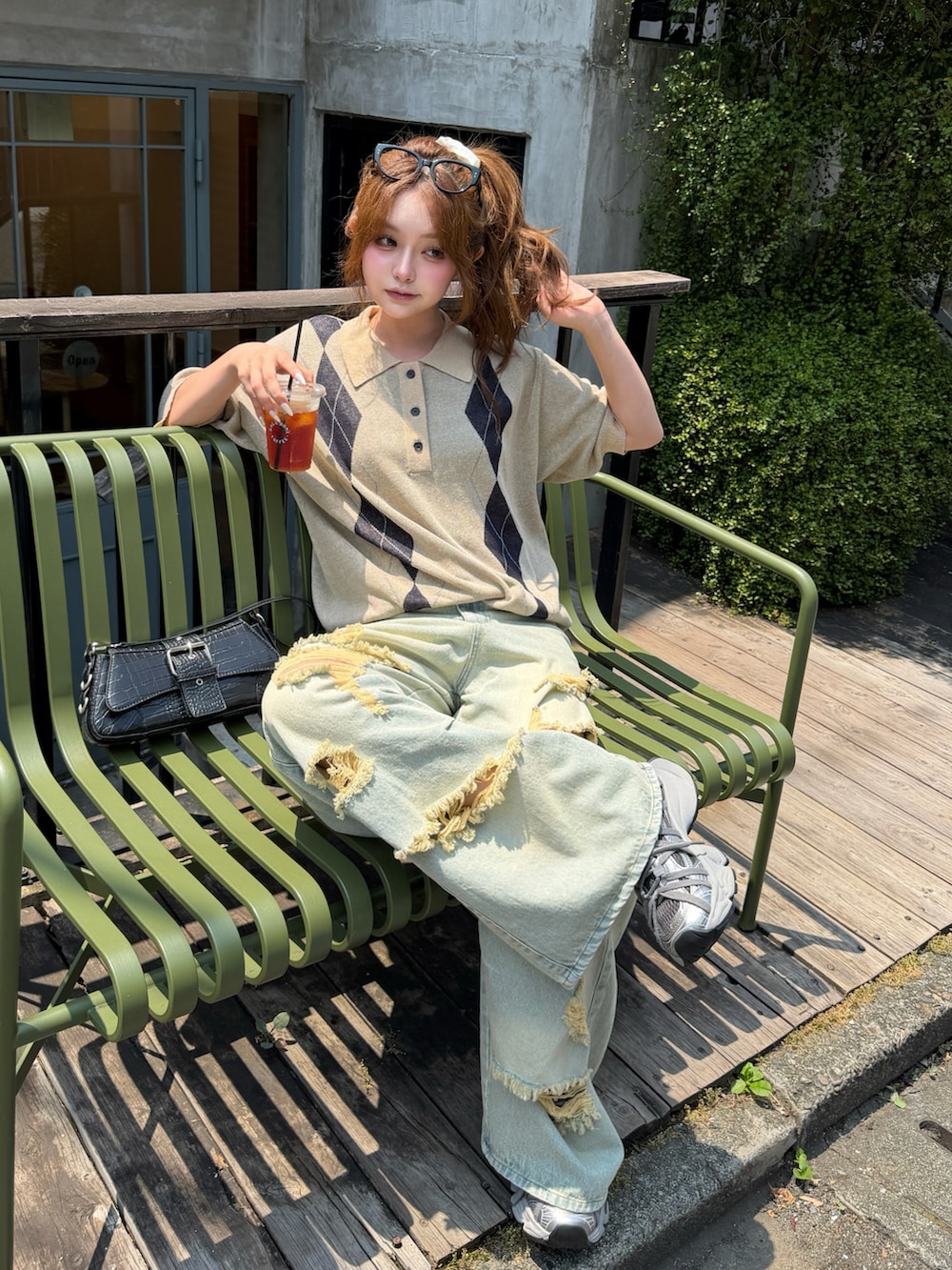 ベージュ系のニット/セーター、ブルー系のデニムパンツ、ブラック系のショルダーバッグを着用したレディースの夏コーディネートの3枚目の写真
