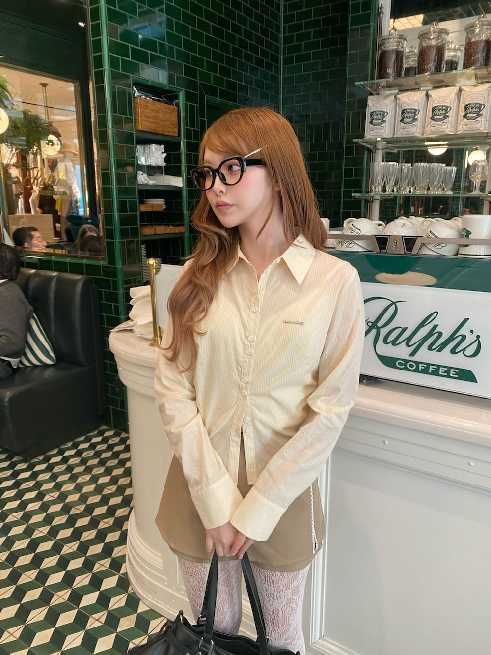 ベージュ系のスカート、ブラック系のショルダーバッグ、イエロー系のシャツ/ブラウスを着用したレディースの冬コーディネートの2枚目の写真