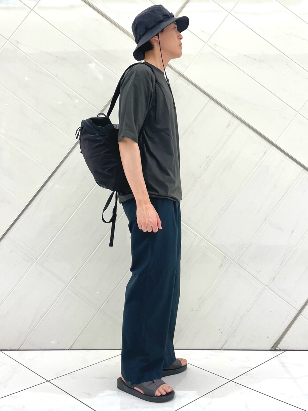 グレー系のサンダル、グレー系のTシャツ/カットソー、ブラック系のバックパック/リュックを着用したメンズの夏コーディネートの2枚目の写真