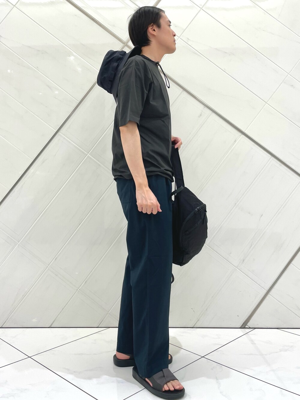 グレー系のサンダル、グレー系のTシャツ/カットソー、ブラック系のバックパック/リュックを着用したメンズの夏コーディネートの5枚目の写真