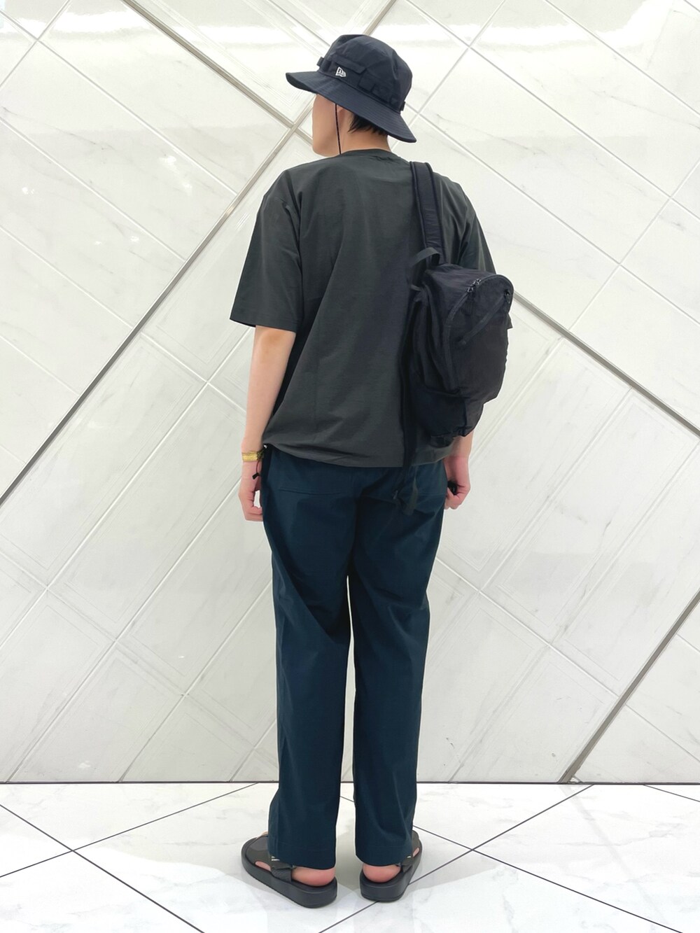 グレー系のサンダル、グレー系のTシャツ/カットソー、ブラック系のバックパック/リュックを着用したメンズの夏コーディネートの3枚目の写真