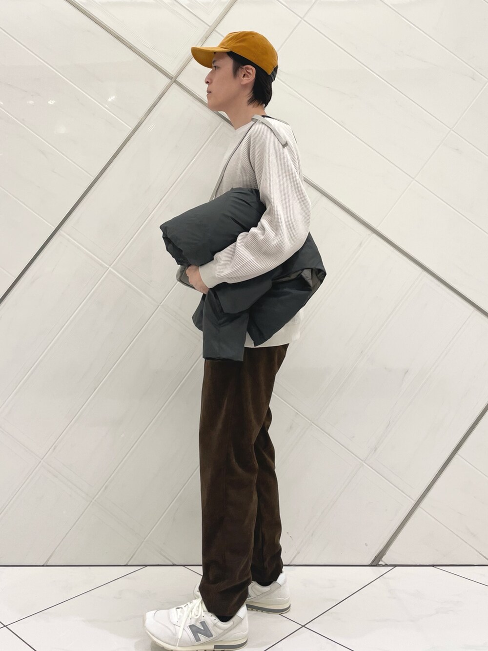 ブラウン系のダウンジャケット/コート、ベージュ系のTシャツ/カットソー、ブラウン系のその他パンツを着用したメンズの秋コーディネートの5枚目の写真