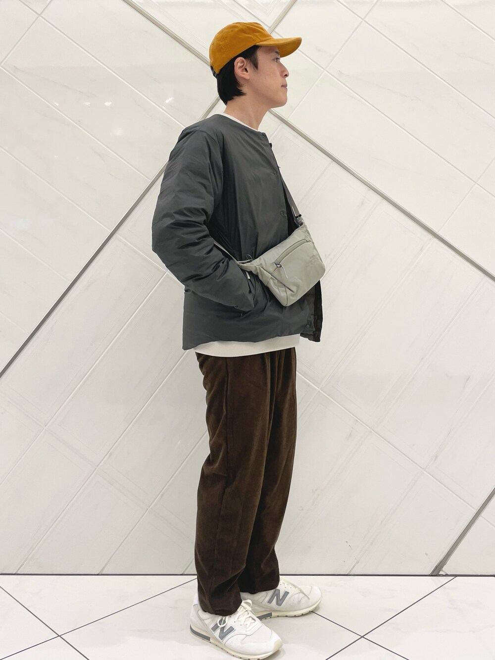 ブラウン系のダウンジャケット/コート、ベージュ系のTシャツ/カットソー、ブラウン系のその他パンツを着用したメンズの秋コーディネートの2枚目の写真