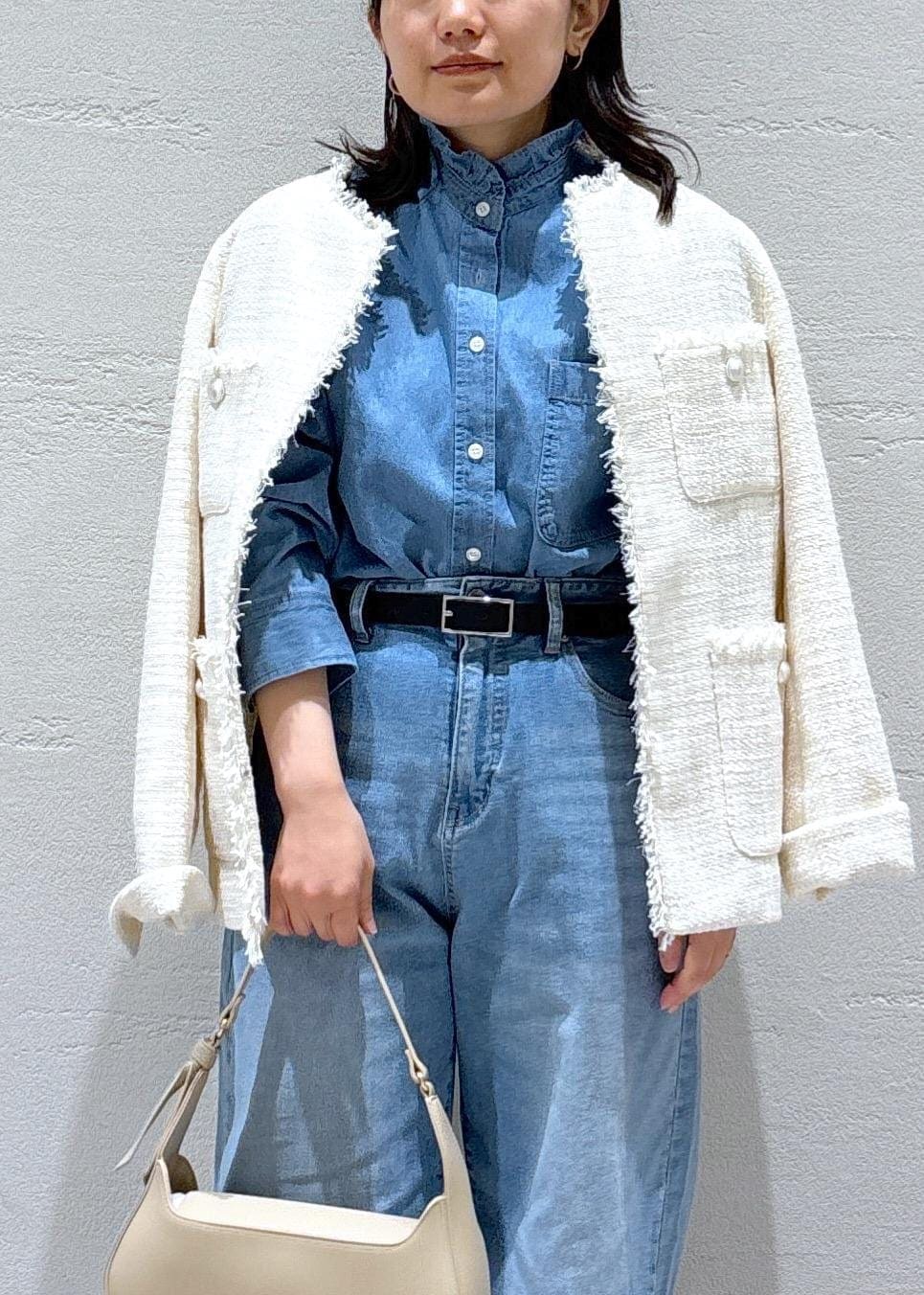 ブルー系のデニムパンツ、ベージュ系のハンドバッグ、ホワイト系のノーカラージャケットを着用したレディースの冬コーディネートの4枚目の写真