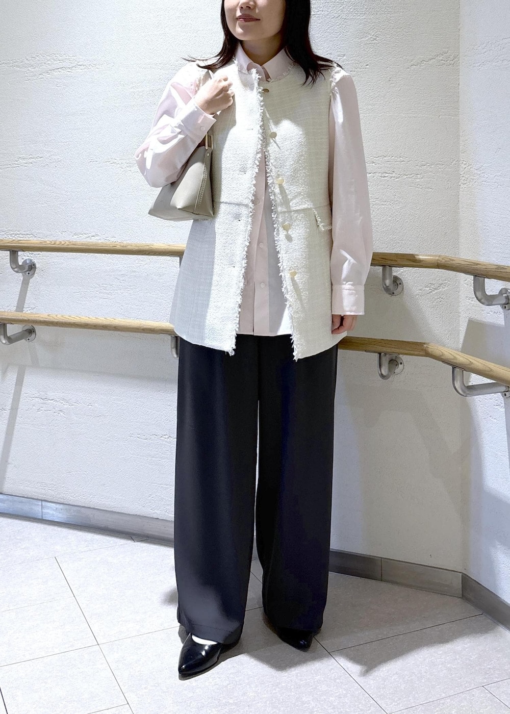 ベージュ系のショルダーバッグ、グレー系のベスト、ピンク系のシャツ/ブラウスを着用したレディースの冬コーディネートの2枚目の写真