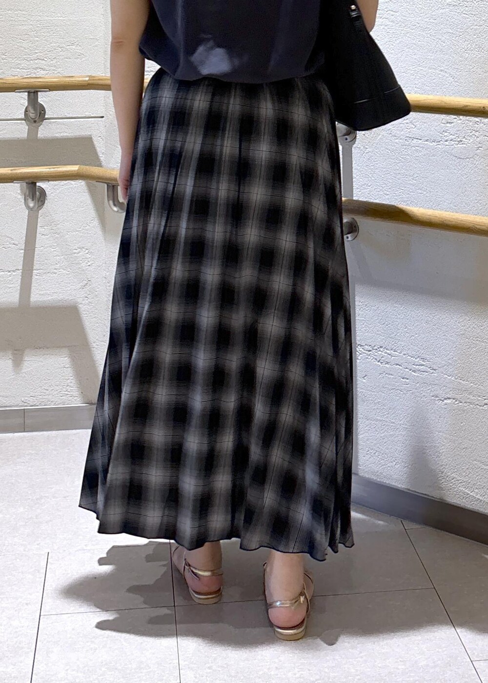ゴールド系のサンダル、ブラック系のスカート、グレー系のTシャツ/カットソーを着用したレディースの夏コーディネートの8枚目の写真