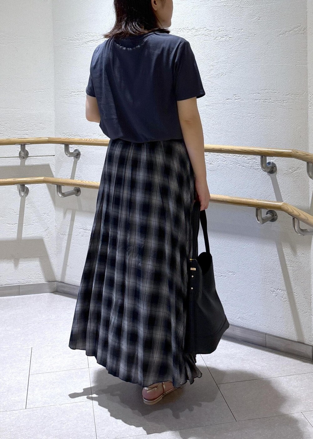 ゴールド系のサンダル、ブラック系のスカート、グレー系のTシャツ/カットソーを着用したレディースの夏コーディネートの4枚目の写真