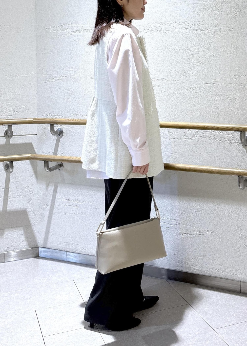 ベージュ系のショルダーバッグ、グレー系のベスト、ピンク系のシャツ/ブラウスを着用したレディースの冬コーディネートの3枚目の写真