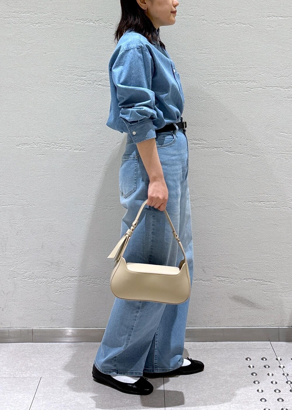 ブルー系のデニムパンツ、ベージュ系のハンドバッグ、ホワイト系のノーカラージャケットを着用したレディースの冬コーディネートの8枚目の写真