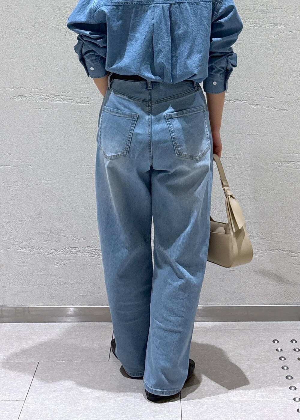 ブルー系のデニムパンツ、ベージュ系のハンドバッグ、ホワイト系のノーカラージャケットを着用したレディースの冬コーディネートの10枚目の写真