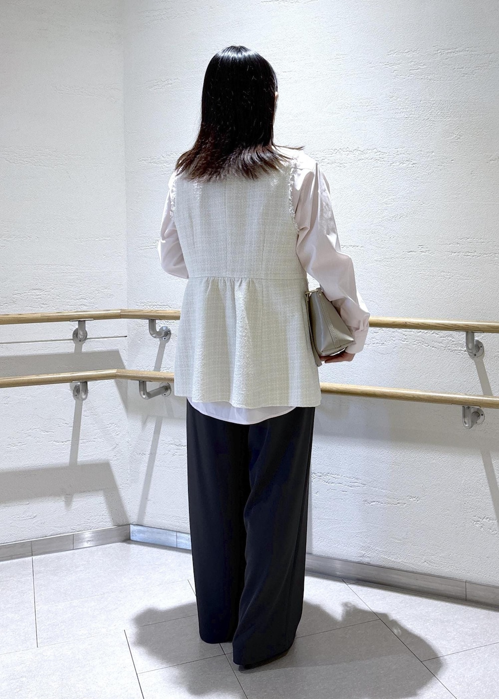 ベージュ系のショルダーバッグ、グレー系のベスト、ピンク系のシャツ/ブラウスを着用したレディースの冬コーディネートの4枚目の写真