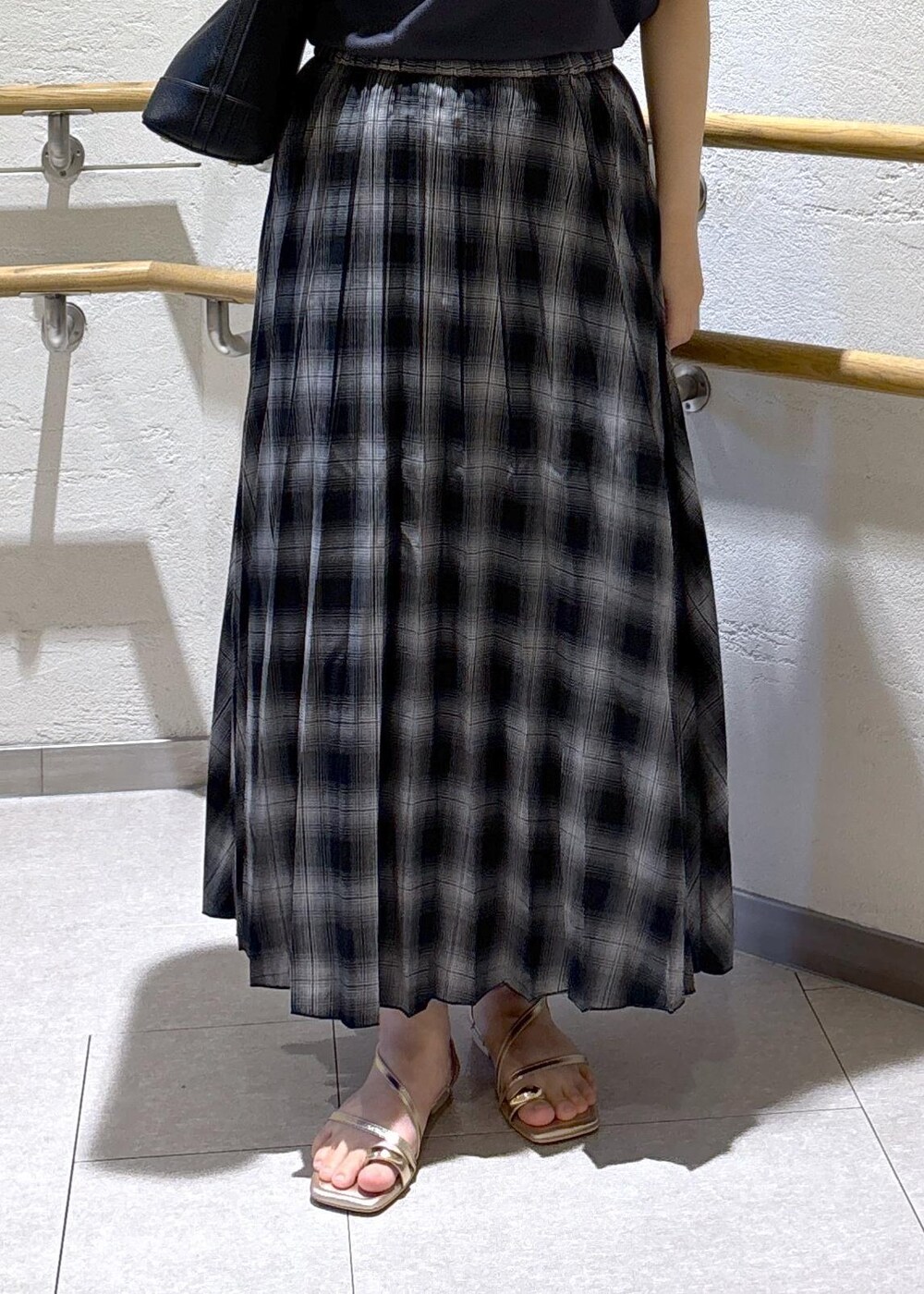 ゴールド系のサンダル、ブラック系のスカート、グレー系のTシャツ/カットソーを着用したレディースの夏コーディネートの7枚目の写真