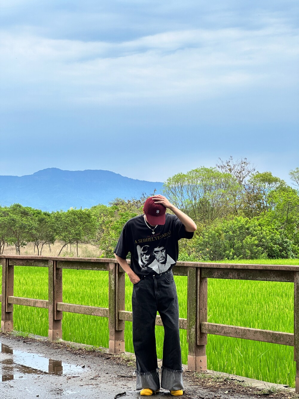 ブラック系のデニムパンツ、イエロー系のスニーカー、シルバー系のアクセサリーを着用したメンズの夏コーディネートの4枚目の写真