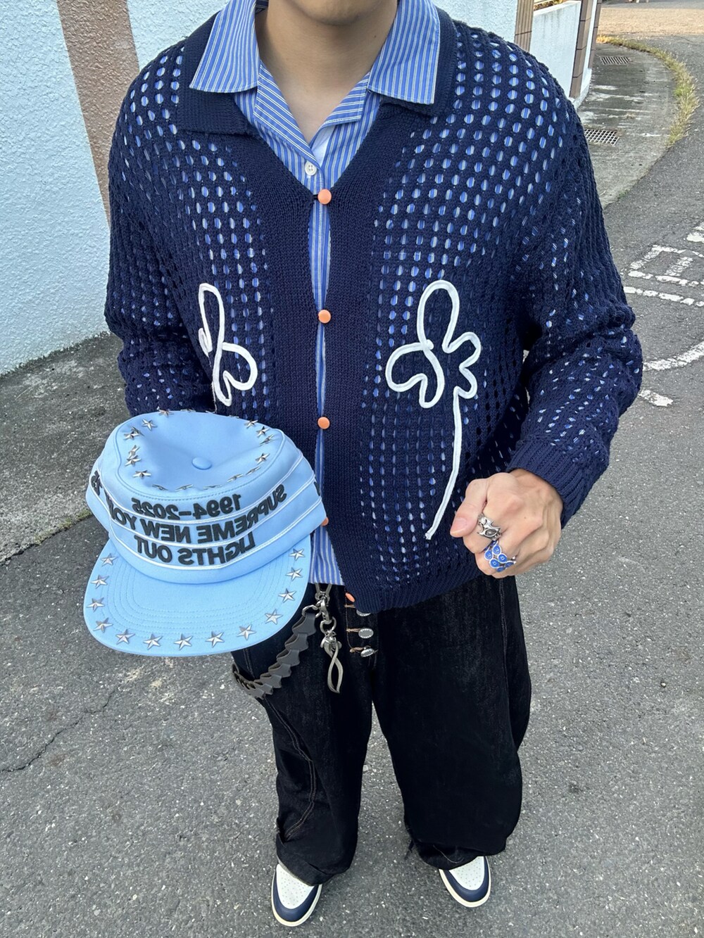 ブルー系のアンサンブル、ブラック系のデニムパンツ、シルバー系のアクセサリーを着用したメンズの秋コーディネートの2枚目の写真