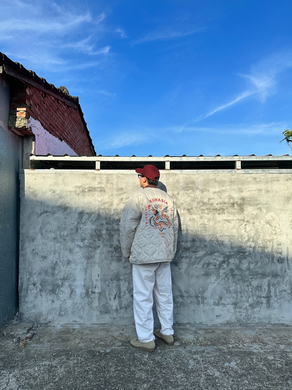 ホワイト系のジャケット/アウター、ブラウン系のニット/セーター、ホワイト系のデニムパンツを着用したメンズの春コーディネートの5枚目の写真