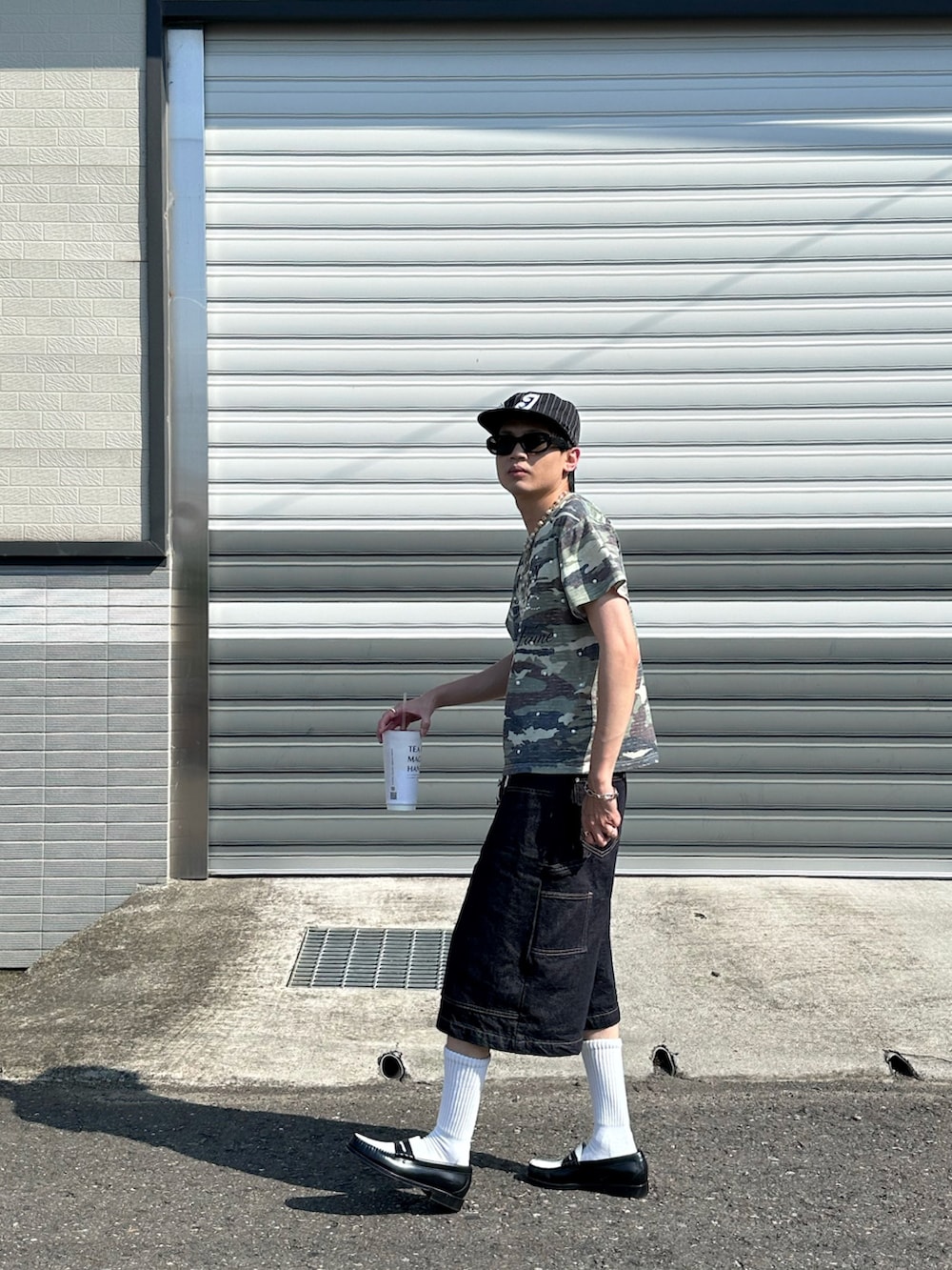 グリーン系のTシャツ/カットソー、ブラック系のデニムパンツ、ブラック系のローファーを着用したメンズの夏コーディネートの4枚目の写真