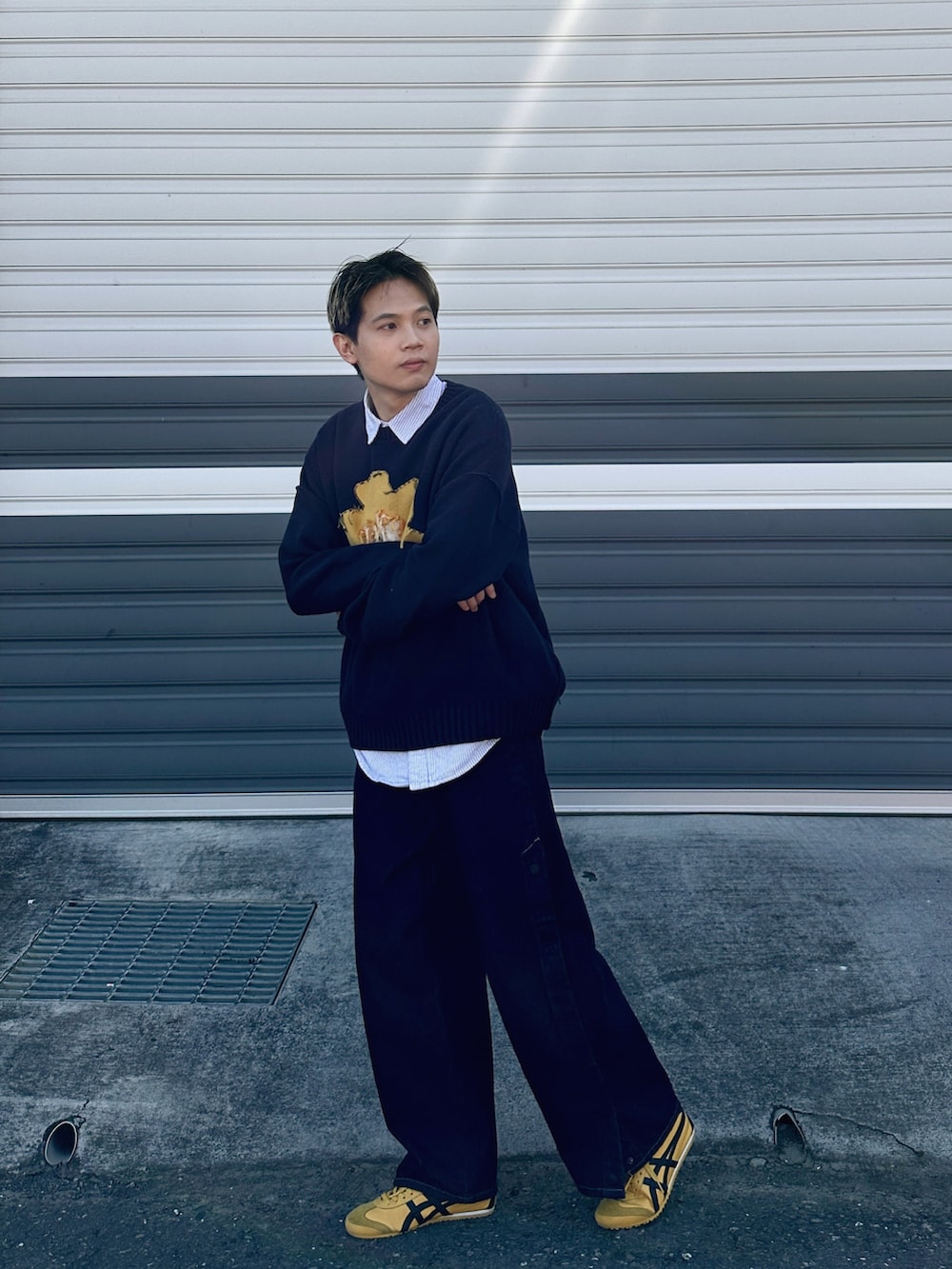 ブルー系のデニムパンツ、イエロー系のスニーカー、ブルー系のニット/セーターを着用したメンズの冬コーディネートの2枚目の写真