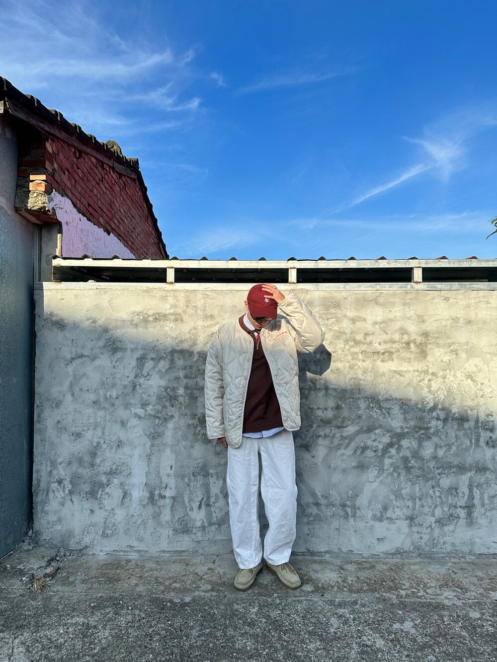 ホワイト系のジャケット/アウター、ブラウン系のニット/セーター、ホワイト系のデニムパンツを着用したメンズの春コーディネートの4枚目の写真