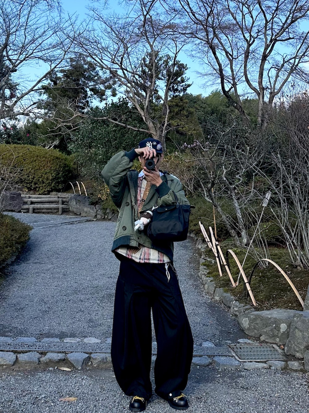 グリーン系のMA-1、ブラック系のトートバッグ、ブラック系のパンツを着用したメンズの冬コーディネートの3枚目の写真