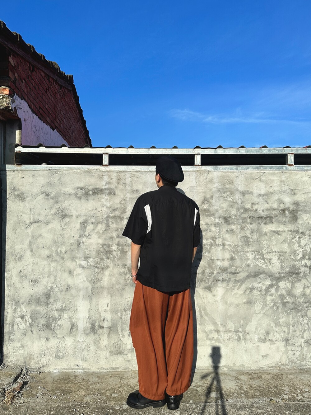 ブラック系のシャツ/ブラウス、オレンジ系のパンツ、ブラック系のキャップを着用したメンズの春コーディネートの4枚目の写真