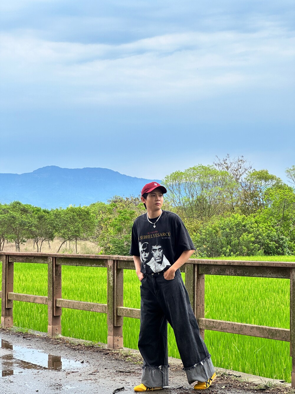 ブラック系のデニムパンツ、イエロー系のスニーカー、シルバー系のアクセサリーを着用したメンズの夏コーディネートの3枚目の写真