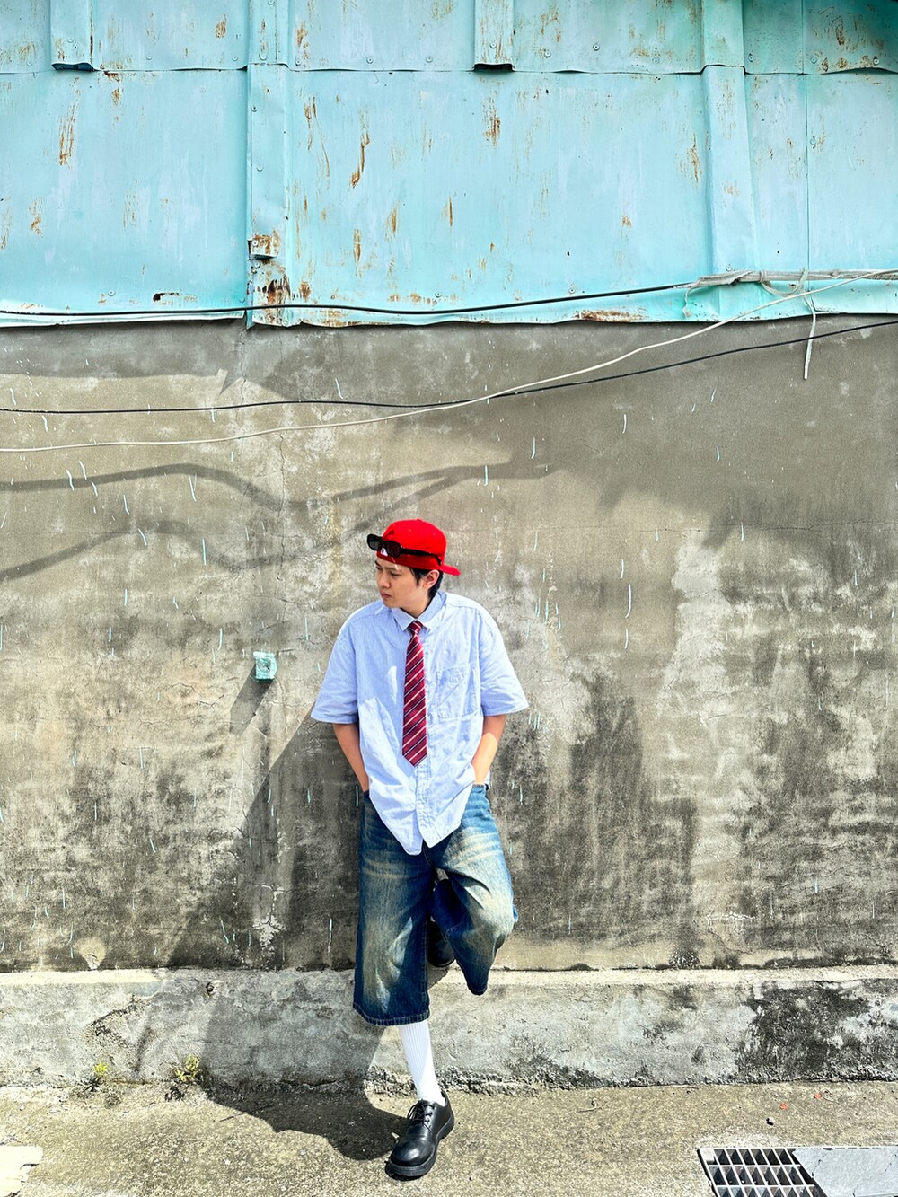 レッド系のキャップ、ブラック系のサングラスを着用したメンズの夏コーディネートの2枚目の写真