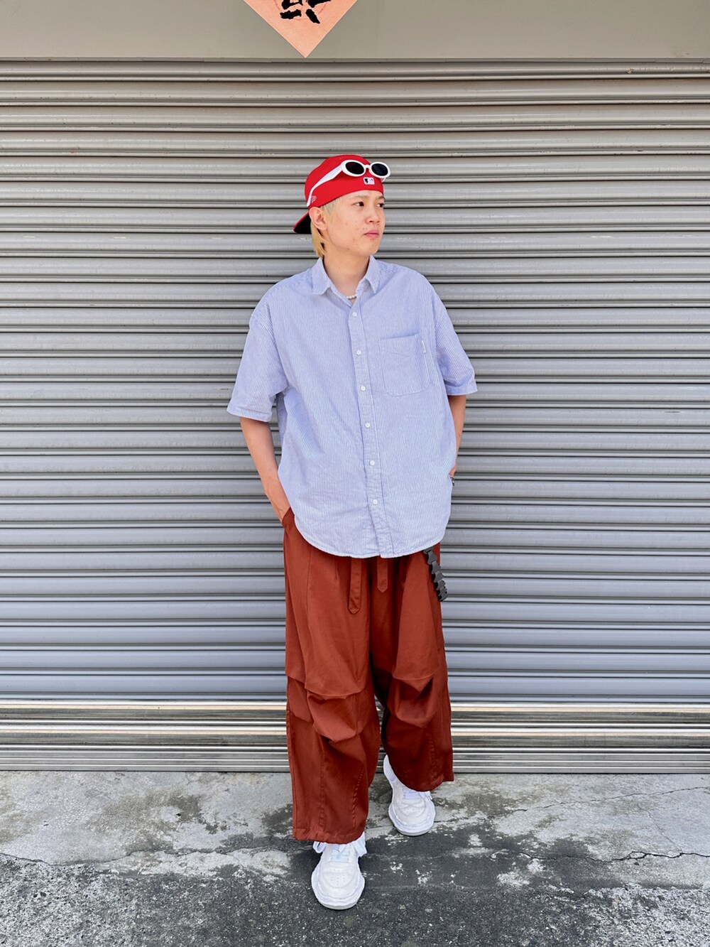 ホワイト系のスニーカー、オレンジ系のパンツ、レッド系のキャップを着用したメンズの夏コーディネートの2枚目の写真