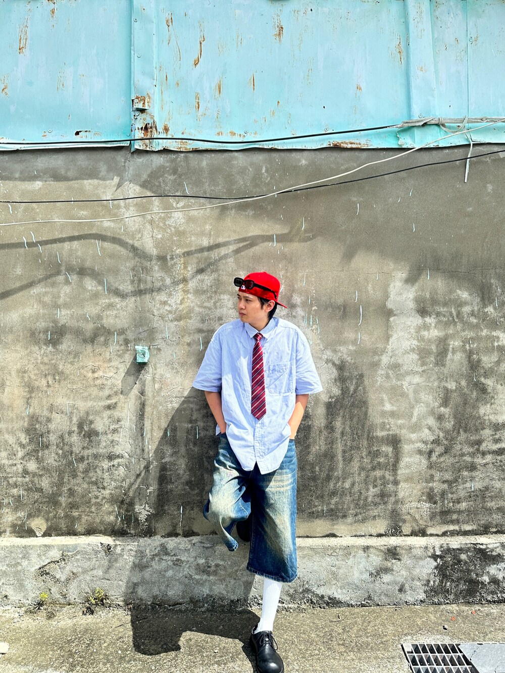 レッド系のキャップ、ブラック系のサングラスを着用したメンズの夏コーディネートの4枚目の写真