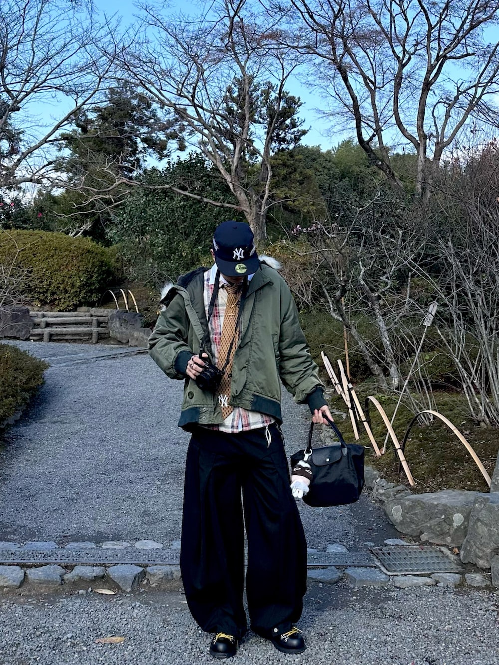 グリーン系のMA-1、ブラック系のトートバッグ、ブラック系のパンツを着用したメンズの冬コーディネートの2枚目の写真