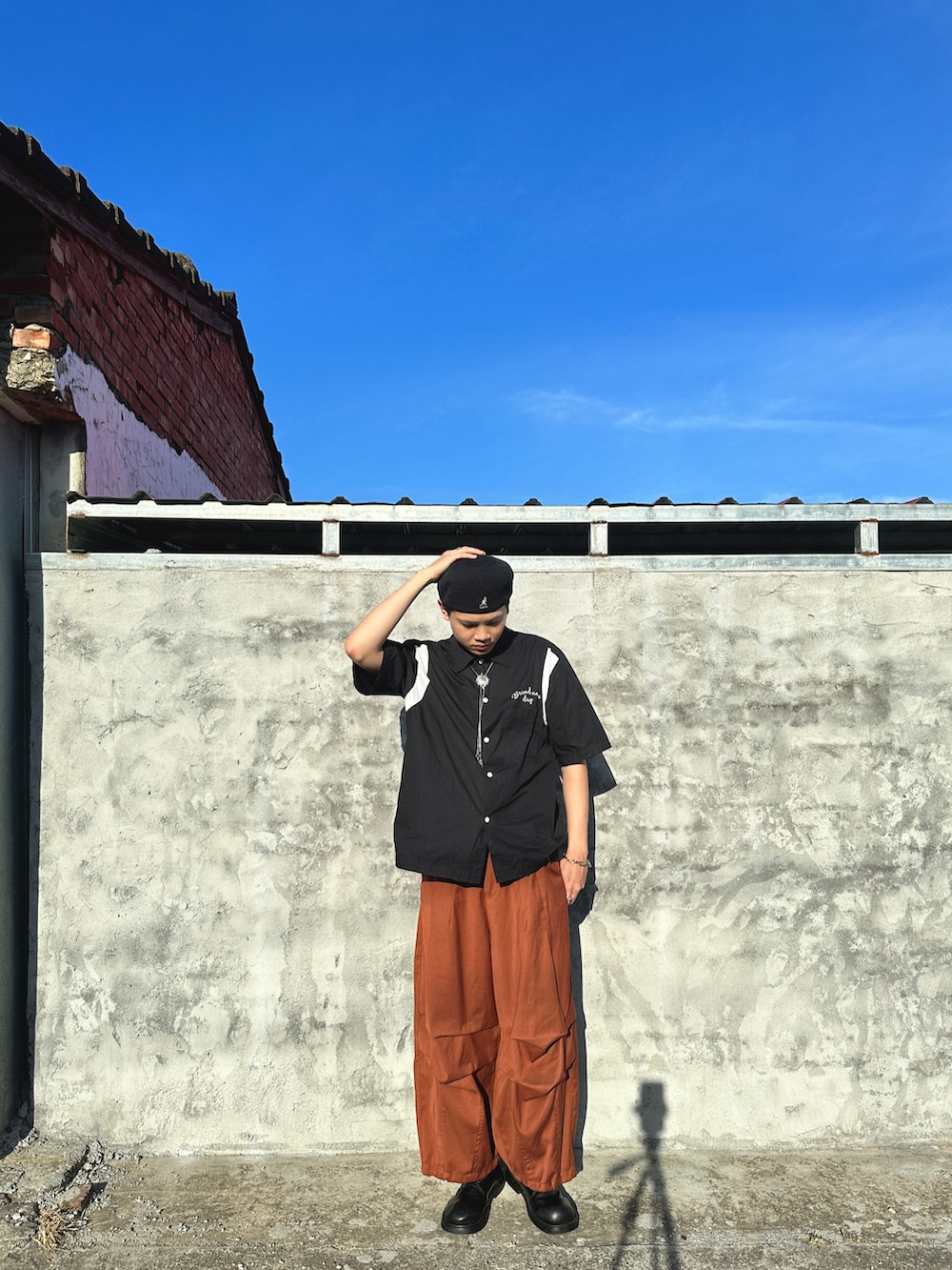 ブラック系のシャツ/ブラウス、オレンジ系のパンツ、ブラック系のキャップを着用したメンズの春コーディネートの5枚目の写真