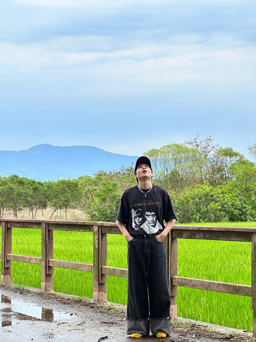 ブラック系のデニムパンツ、イエロー系のスニーカー、シルバー系のアクセサリーを着用したメンズの夏コーディネートの2枚目の写真