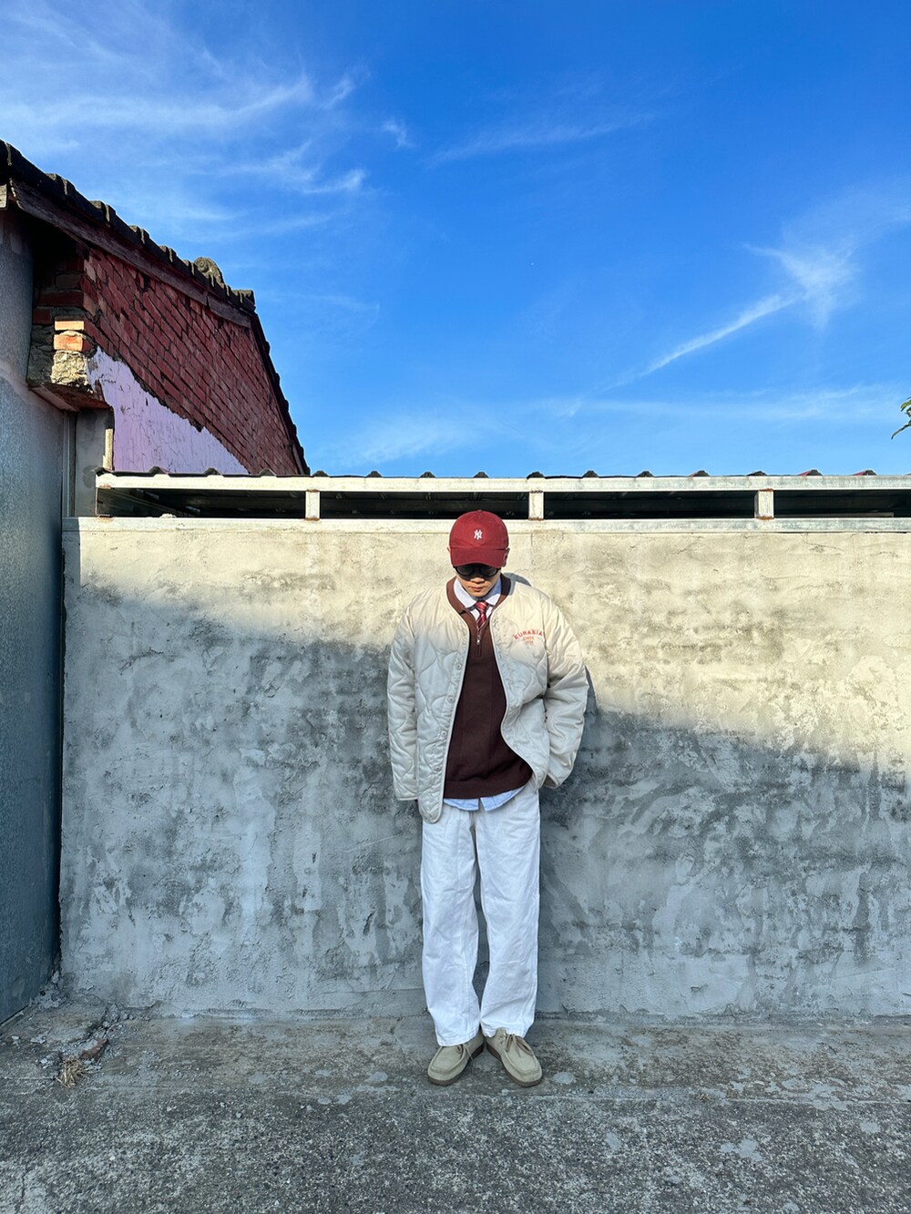 ホワイト系のジャケット/アウター、ブラウン系のニット/セーター、ホワイト系のデニムパンツを着用したメンズの春コーディネートの2枚目の写真