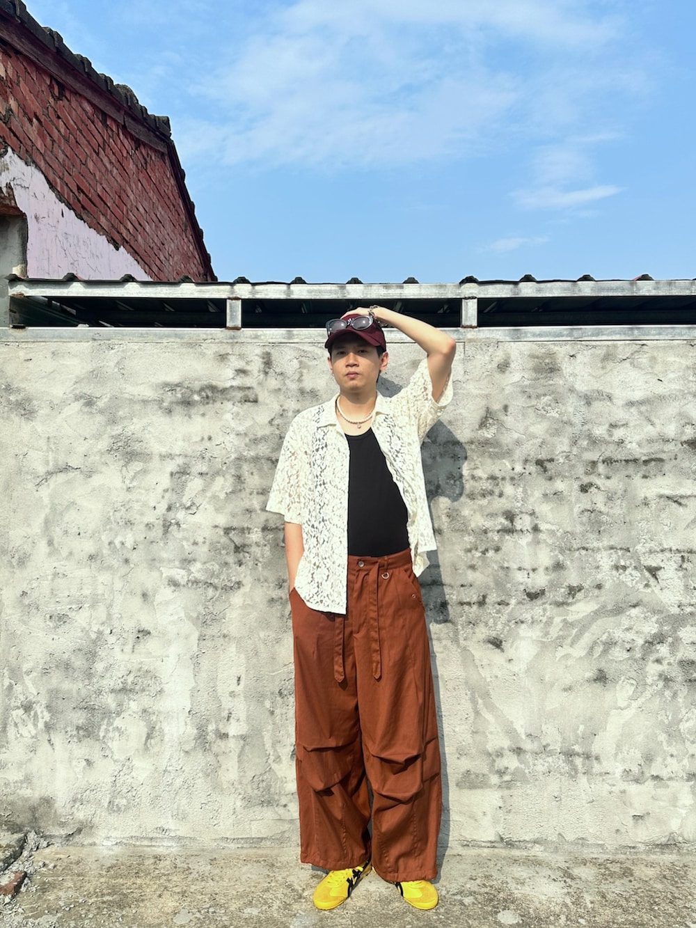 オレンジ系のパンツ、ホワイト系のトップス、ブラック系のタンクトップを着用したメンズの春コーディネートの2枚目の写真