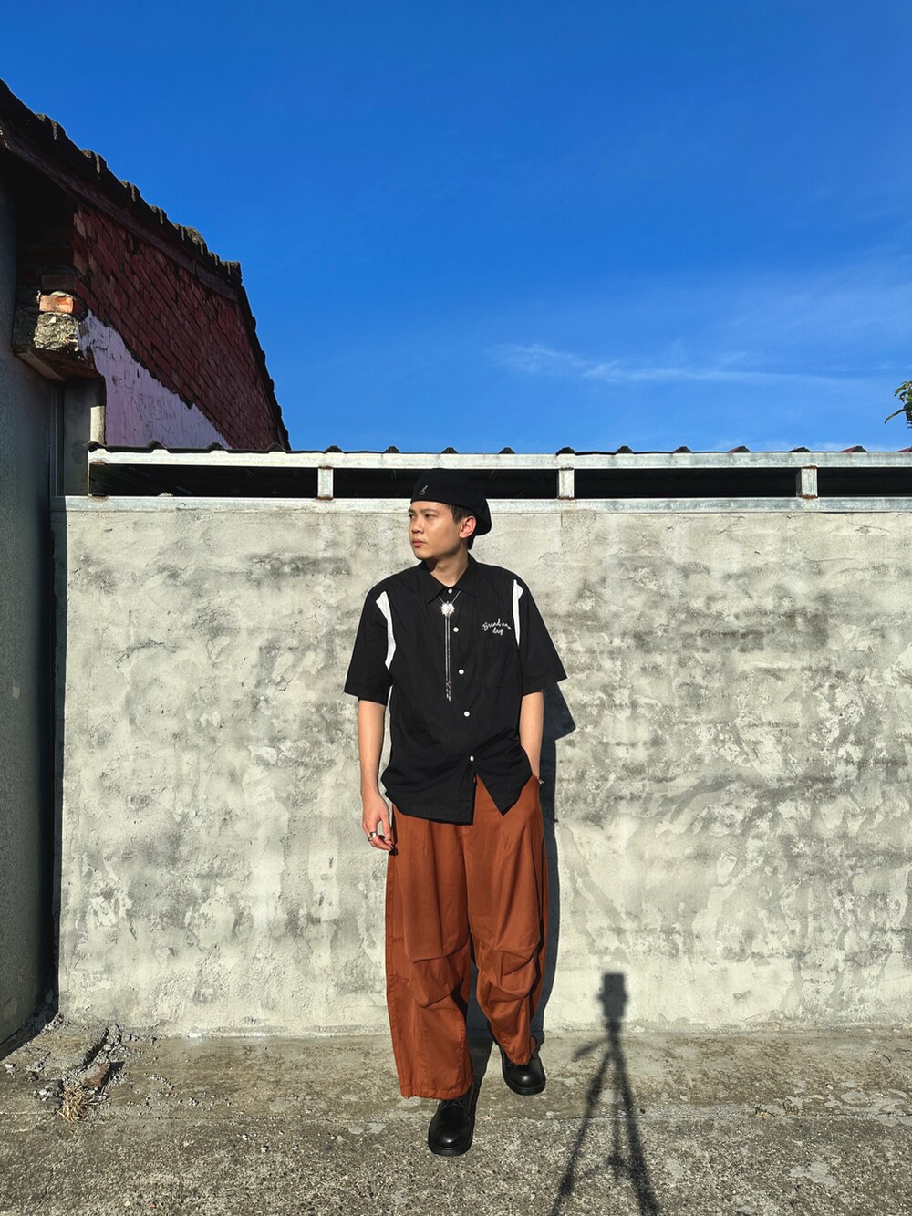 ブラック系のシャツ/ブラウス、オレンジ系のパンツ、ブラック系のキャップを着用したメンズの春コーディネートの2枚目の写真