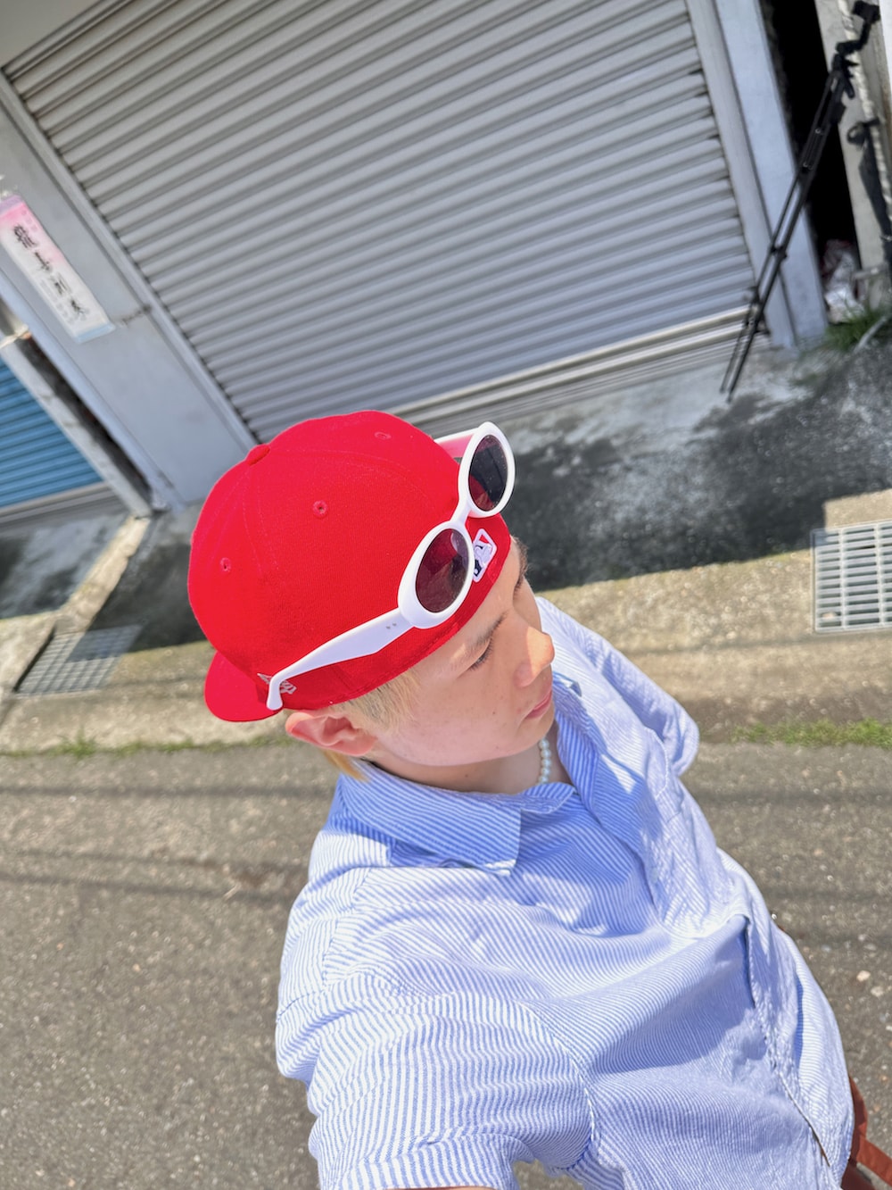 ホワイト系のスニーカー、オレンジ系のパンツ、レッド系のキャップを着用したメンズの夏コーディネートの5枚目の写真