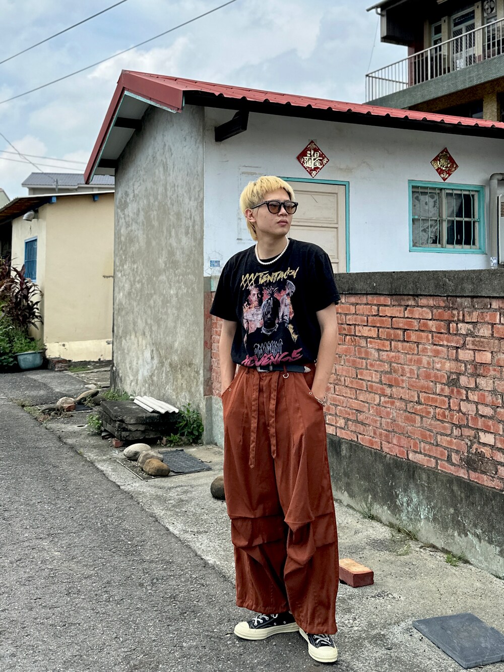 オレンジ系のパンツ、ブラック系のスニーカー、オレンジ系のサングラスを着用したメンズの夏コーディネートの3枚目の写真